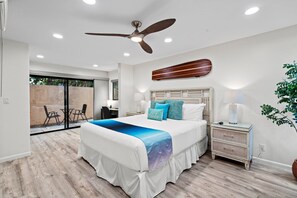 A bedroom with a bed, a ceiling fan, a nightstand, and a view of an outdoor area. - Wailea Ekahi 24B - Modern Garden Retreat w/ Lanai, Split AC & Stylish Renovation (Kihei)