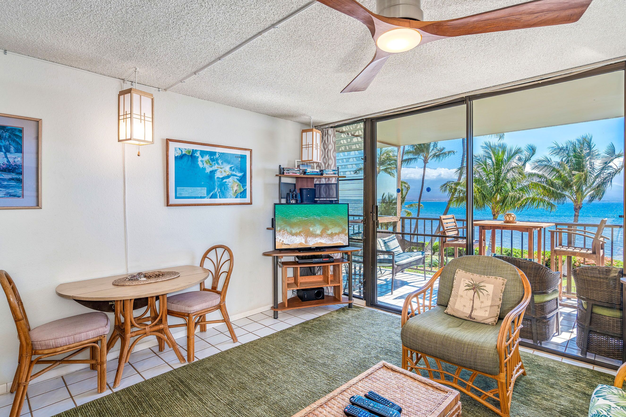 A living room with a TV, wooden furniture, and a view of the ocean.