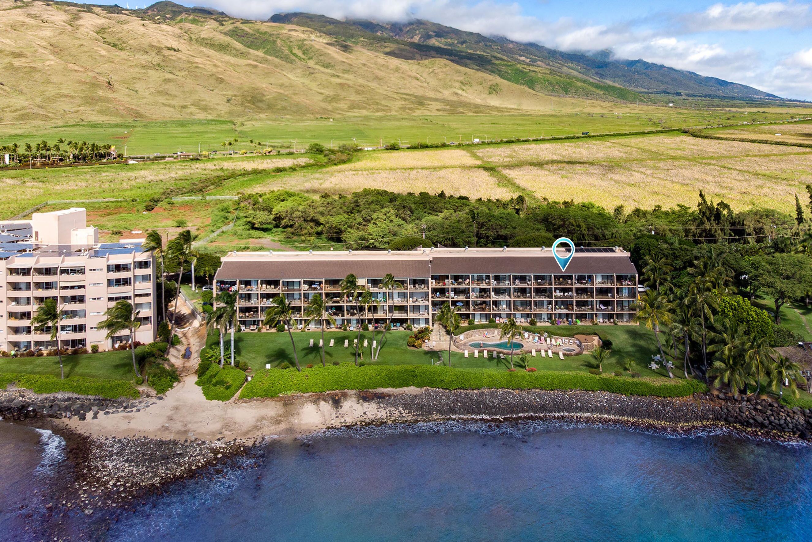 A hotel with multiple floors, a pool, and a view of the surrounding landscape.