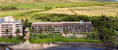 A hotel with multiple floors, a pool, and a view of the surrounding landscape.