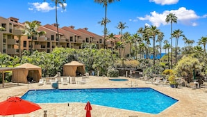 Área de piscina en un complejo turístico, con varias piscinas, sillas de descanso y palmeras.