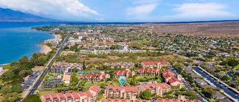 Vista aérea de una zona residencial costera con varios edificios de apartamentos, una playa y cielo despejado.