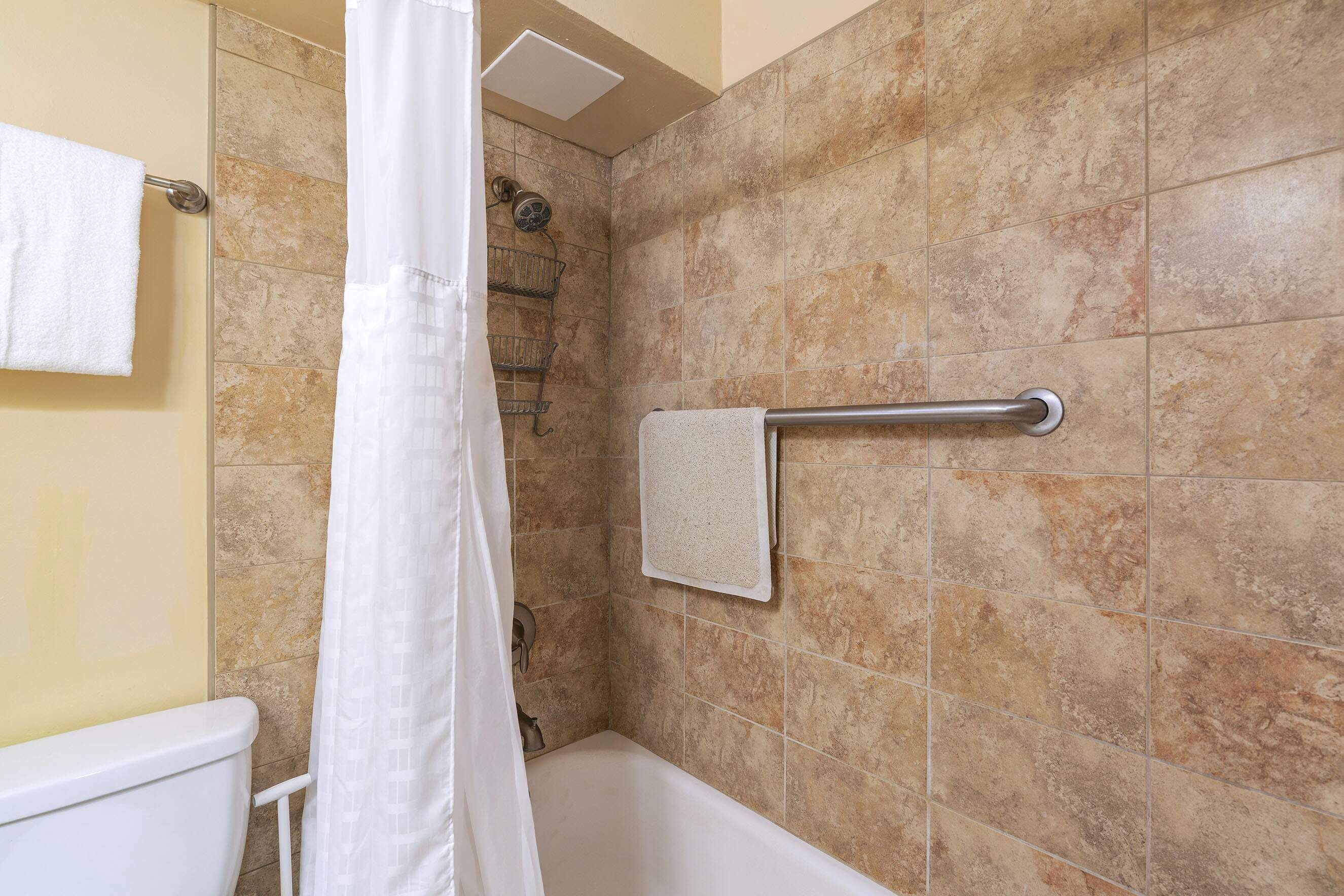 A bathroom with a shower, a towel rack, and a toilet.