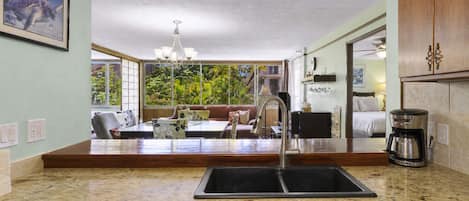 A kitchen with a built-in dishwasher, a coffee maker, and a view of a balcony with a dining area.