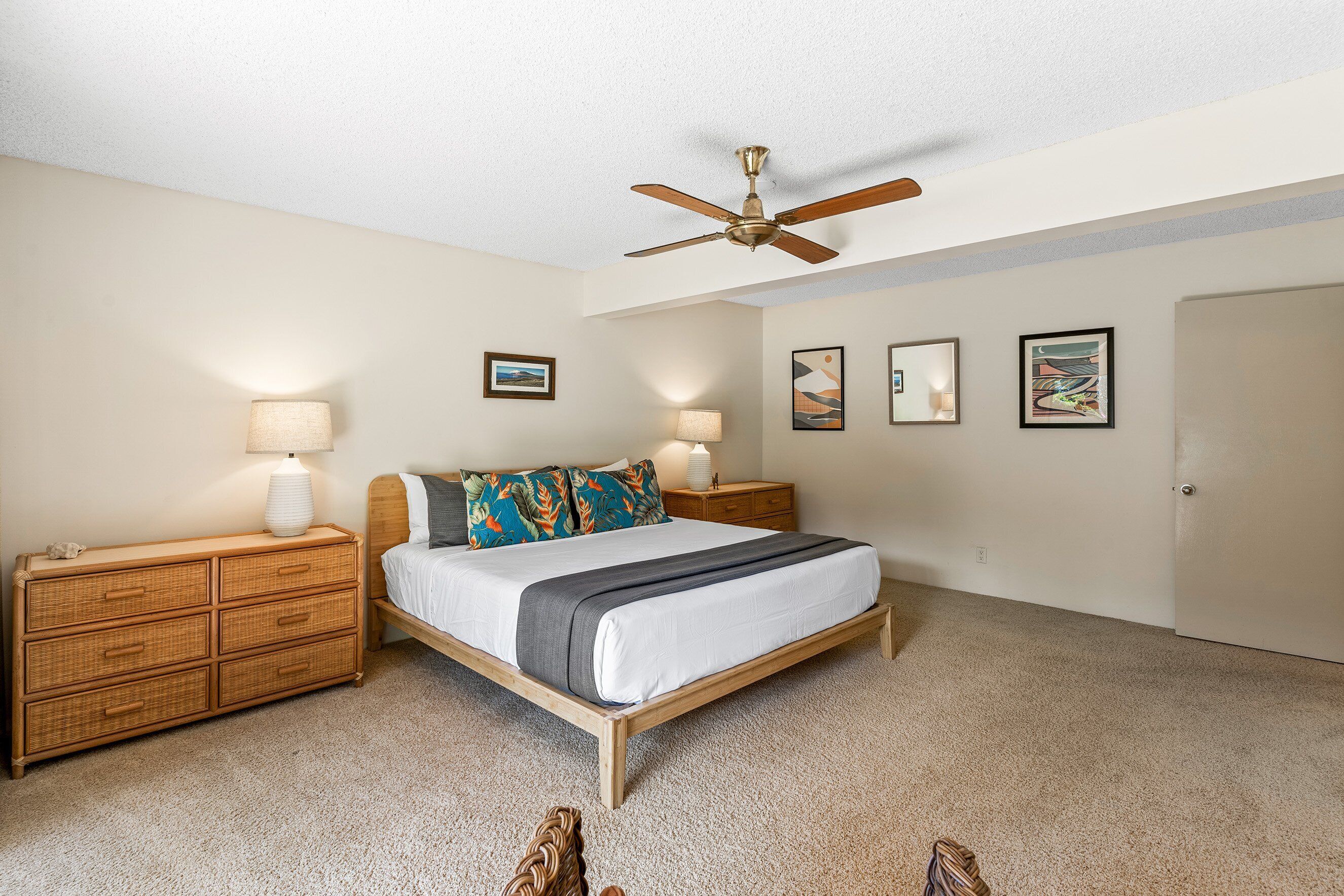 A bedroom with a bed, two bedside tables, a ceiling fan, and wall art.