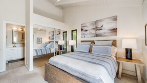 A bedroom with a large bed, bedside tables, a mirror, and abstract wall art. - Extraordinary Molokini Views, Spectacular Renovation, New Split AC, Ocean Views! (Kihei)