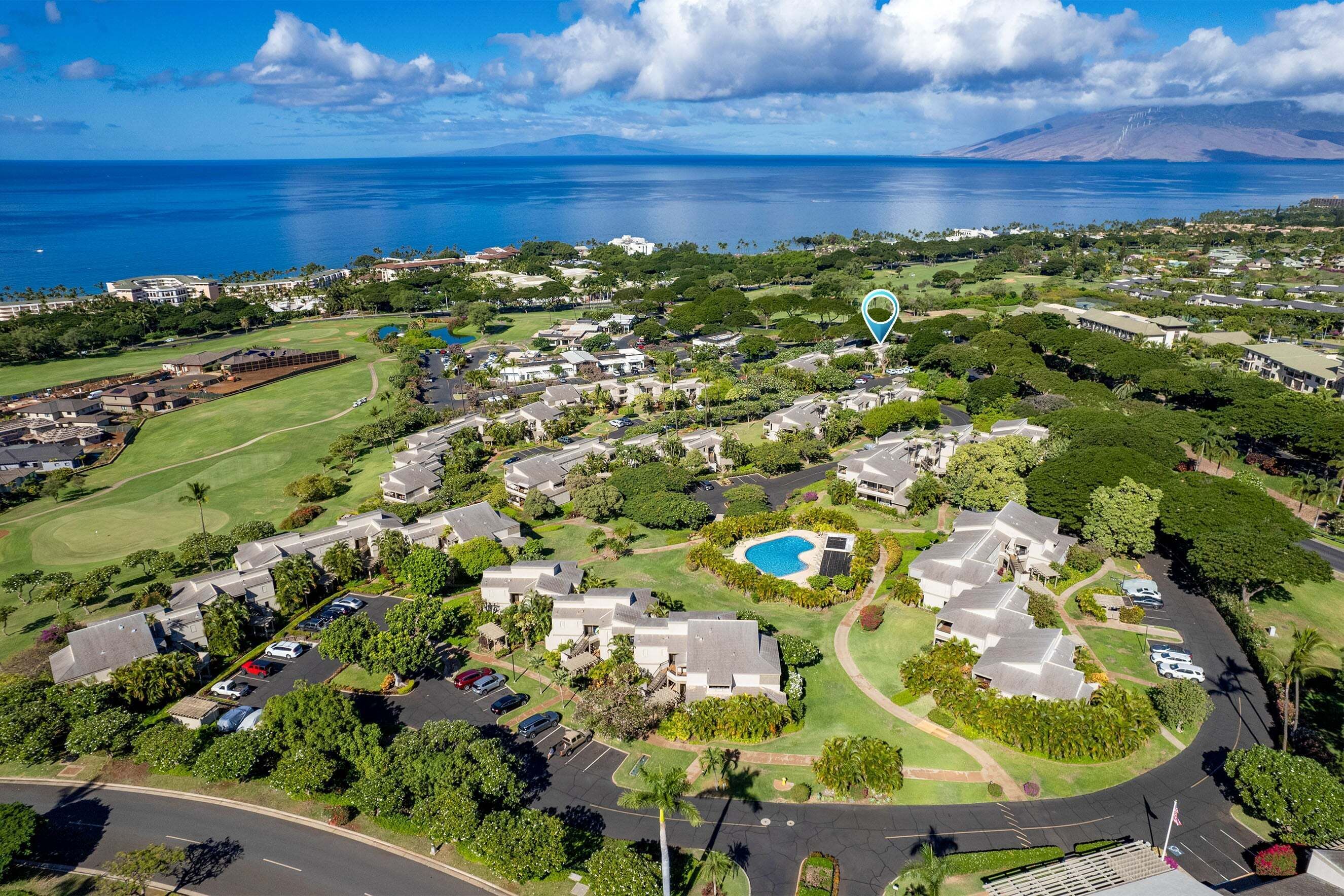 An aerial view of a residential area with houses, a golf course, and a large body of water.