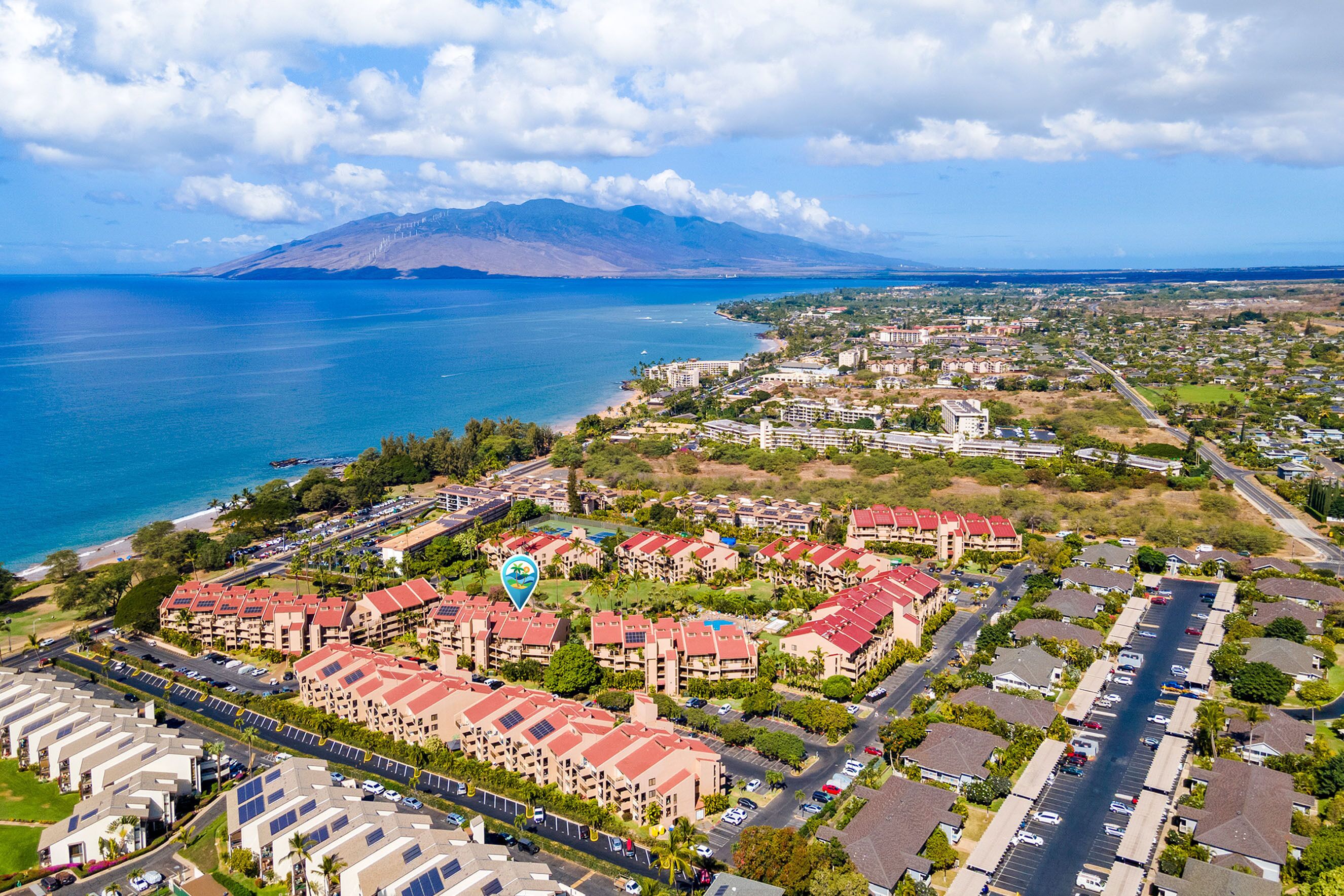 Vue aérienne d’une zone résidentielle côtière, avec des immeubles d’habitation, des routes et une vaste étendue d’eau.