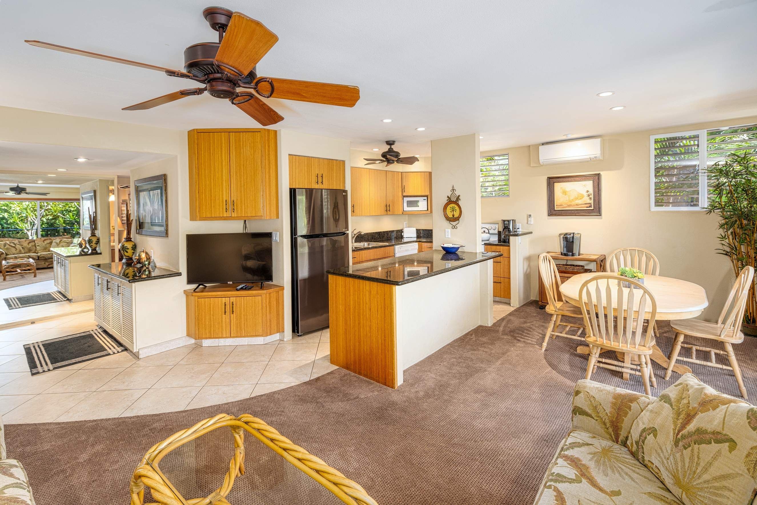 A modern kitchen with wooden cabinets, a central island, and a ceiling fan.