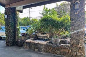 A stone wall with a small water feature and potted plants. - Hale Hui Kai 202 - Keawakapu Beach, Garden Views, Steps to the Beach, Split AC! (Kihei)