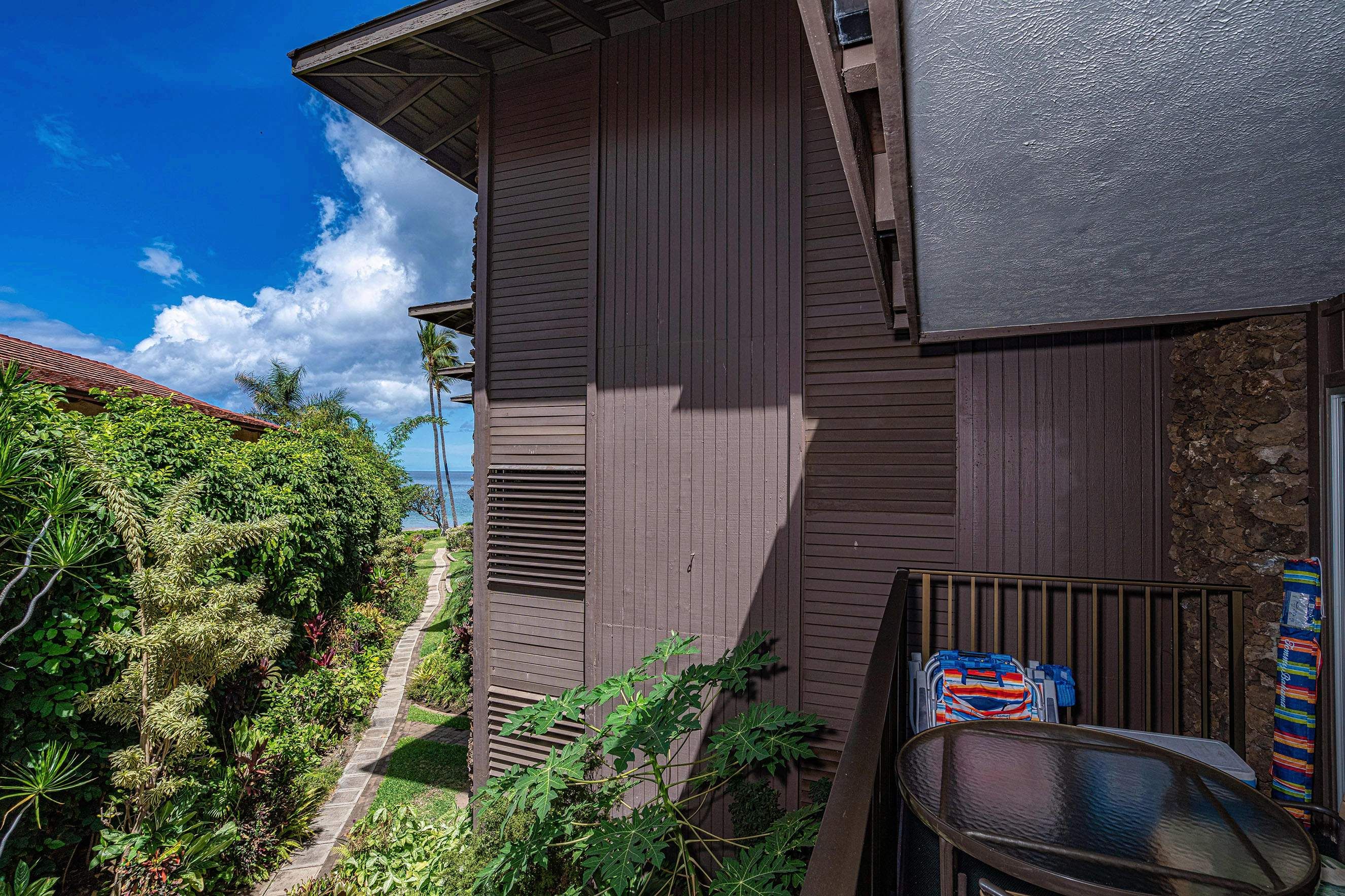 Un immeuble de deux étages doté d’un balcon, d’un mur en pierre et offrant une vue sur la mer.