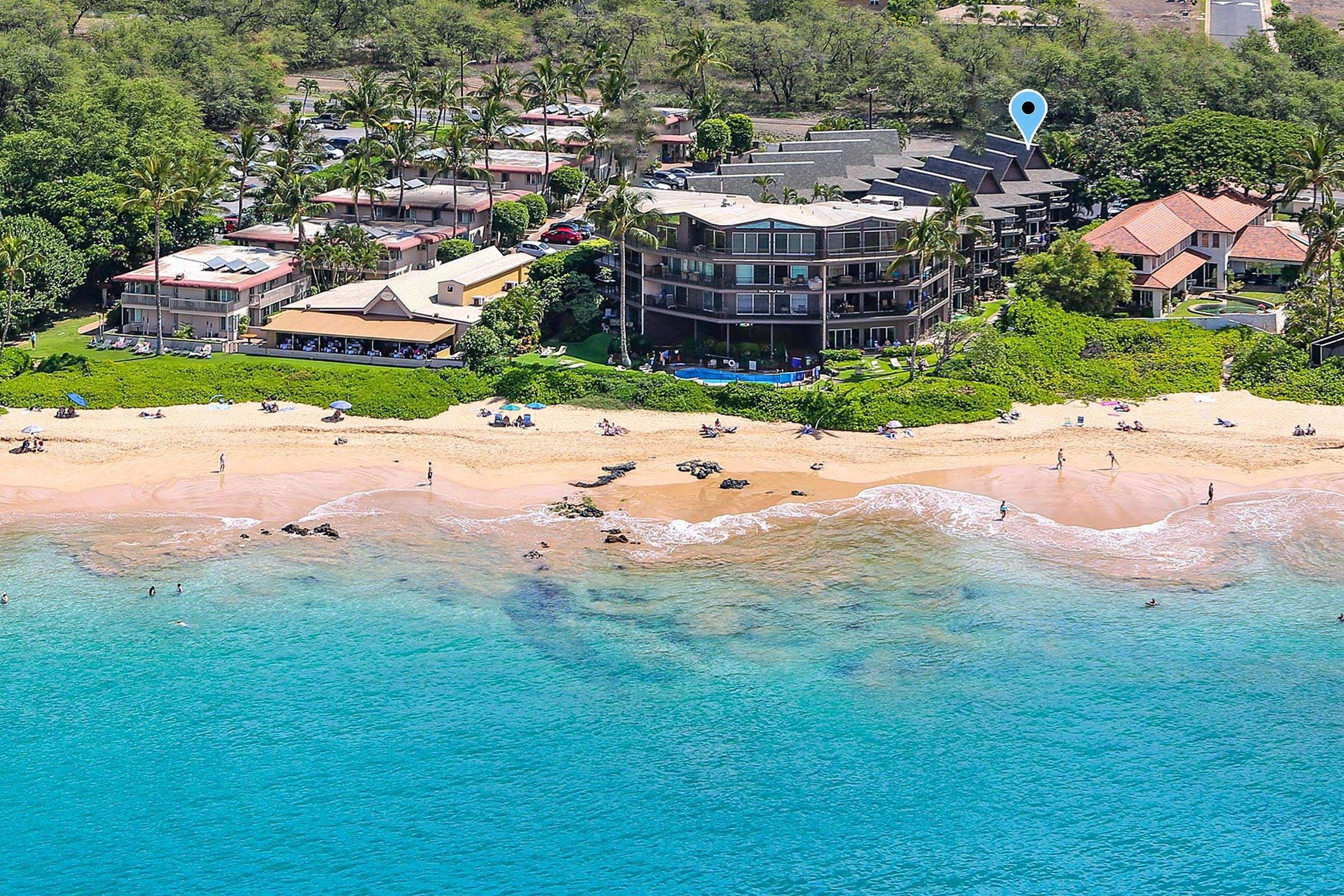 A coastal hotel with multiple buildings, a beach, and clear blue waters.