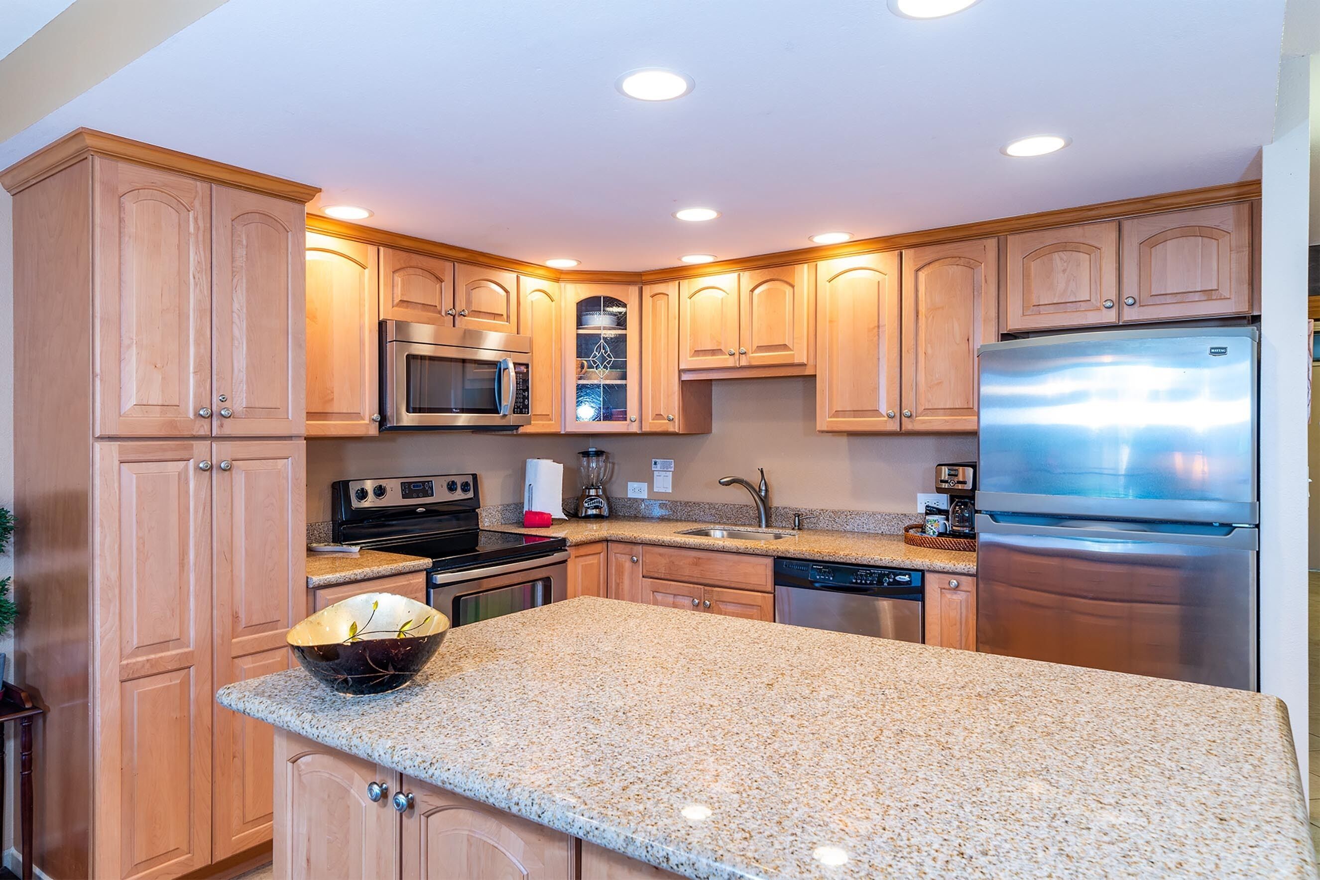 A modern kitchen with granite countertops, stainless steel appliances, and wooden cabinetry.