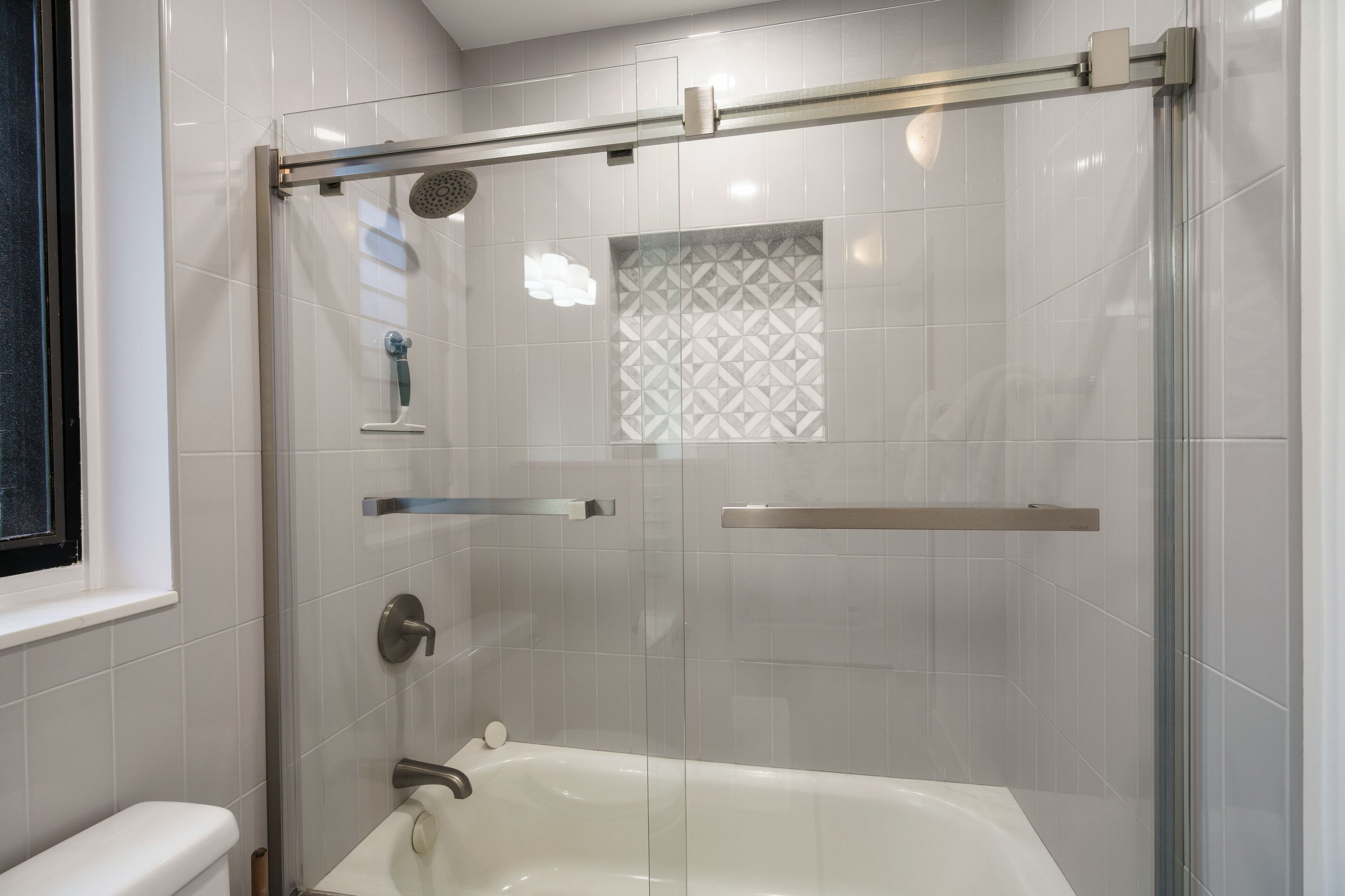 A modern bathroom with a glass-enclosed shower, a bathtub, and a toilet.