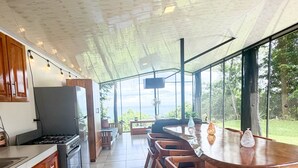 Une cuisine moderne avec un coin repas, de grandes fenêtres et un téléviseur.