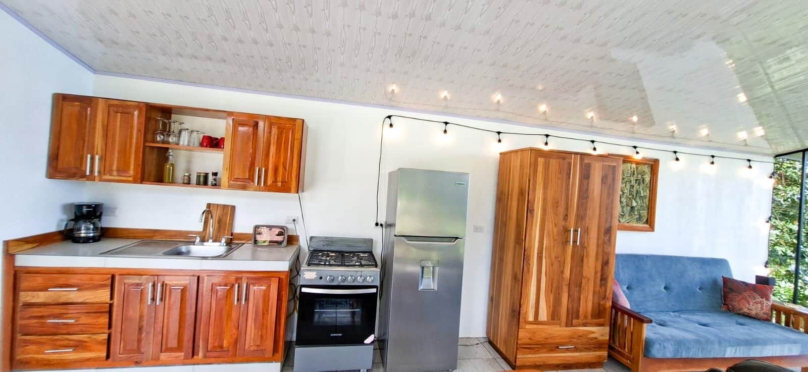 A compact kitchen with wooden cabinets, a gas stove, a refrigerator, and a built-in oven.