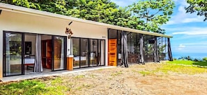 A modern building with large glass doors, a wooden door, and a view of the ocean.