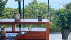 Une table en bois, agrémentée d’un ventilateur et d’objets décoratifs, avec vue sur l’océan.