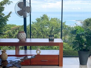 Una mesa de madera con un ventilador, adornos y vista al océano.