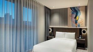 A modern hotel room with a large bed, a nightstand with a phone, and a wall-mounted light. - Hyatt Place Busan Yeonsan (Busan)