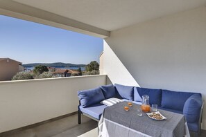 A balcony with a blue sofa, a small table with drinks and snacks, and a clear view of the sea and hills in the background. - Apartment Barbara (74235-A1) - Medulin (Medulin)