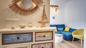 Una habitació amb un mirall decoratiu, una maqueta d'un petit veler i un sofà blau.