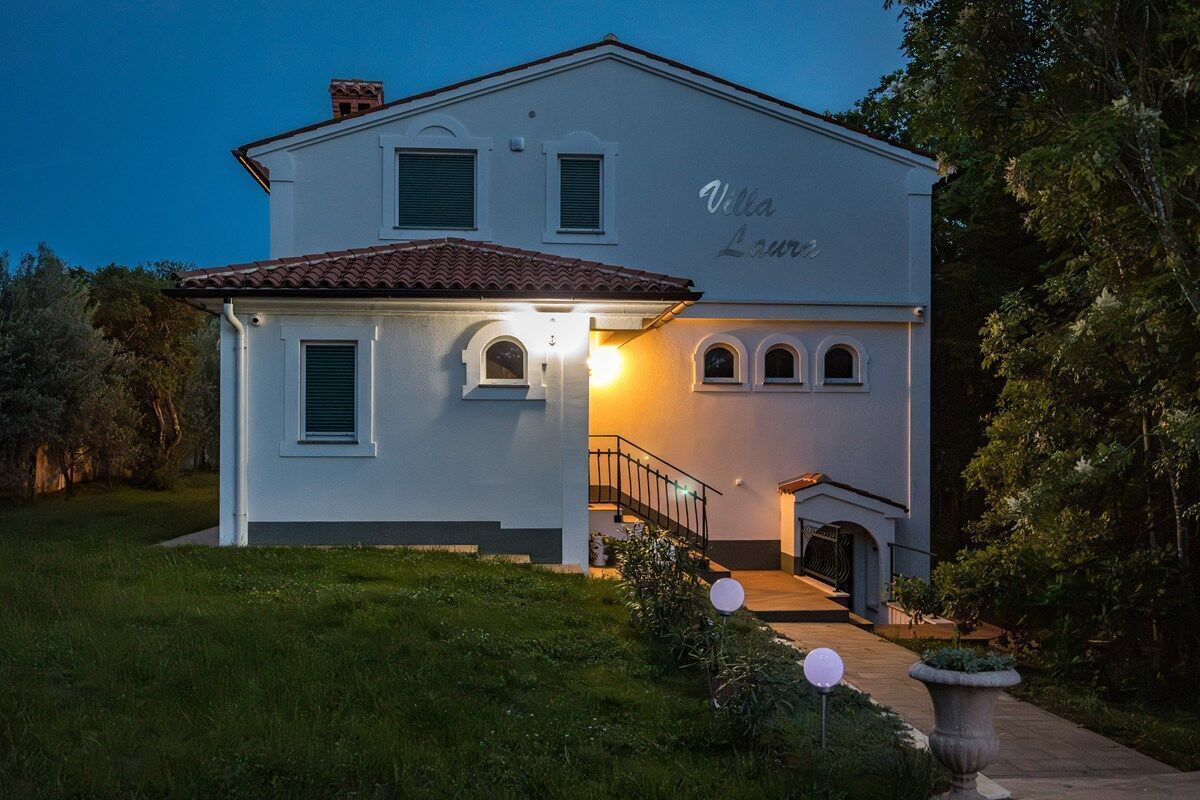 A two-story villa with a white exterior and a tiled roof.