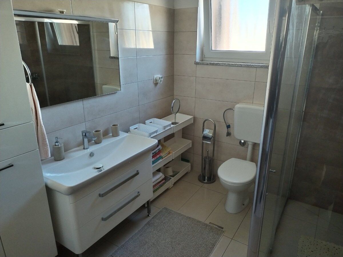 A modern bathroom with a white sink, mirror, and toilet.