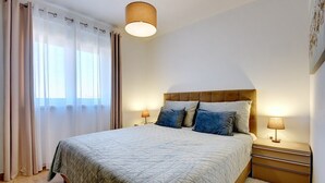 A neatly arranged bedroom with a bed, bedside lamps, and a window with curtains. - Apartment Beach (74259-A1) - Medulin (Medulin)