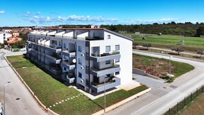 A modern multi-story residential building with balconies, located near a road and green spaces. - Apartment Beach (74259-A1) - Medulin (Medulin)