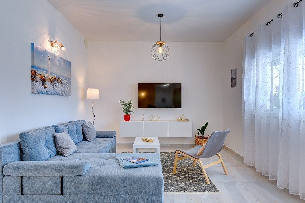 Un soggiorno moderno con un divano, una TV, un tavolino e una poltrona.