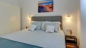 Una cama bien hecha con cabecera, dos lámparas de noche y una mesita de noche con un objeto decorativo.