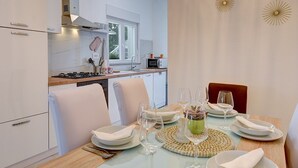 Una cocina moderna con armarios blancos, estufa a gas y microondas. Hay una mesa de comedor con platos, vasos y un centro de mesa.