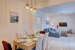 Ett modernt vardagsrum med en matplats, en soffa och en tv, samt en platt-tv som är monterad på väggen.