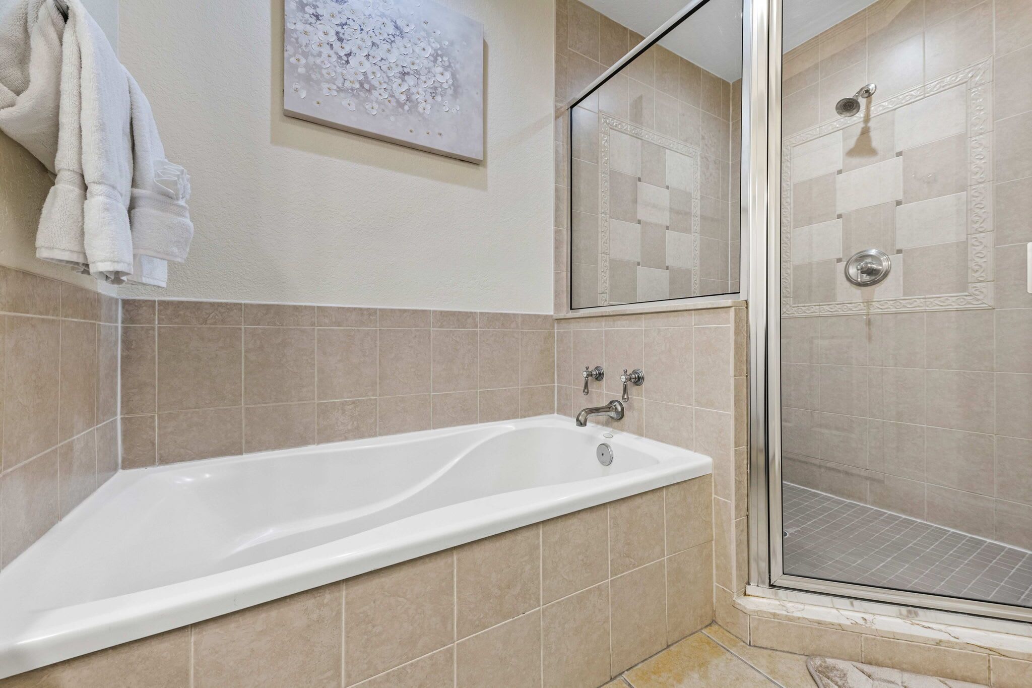 Une salle de bain moderne avec une baignoire, une cabine de douche en verre et un porte-serviettes avec des serviettes pliées.