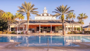 A hotel with a pool, palm trees, and a covered patio area. - Sandy Ridge Retreat Just Steps from the Splash Pad (Kissimmee)