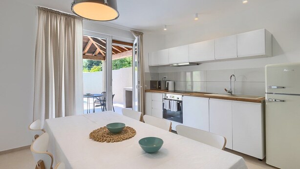 Een moderne keuken met witte kastjes, een houten aanrechtblad en een inbouwoven.