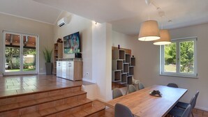 Una cocina amplia con comedor, estanterías empotradas y una escalera que lleva a un espacio exterior.