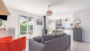 Una sala de estar moderna con un sofá gris, un sillón rojo y una cocina al fondo.