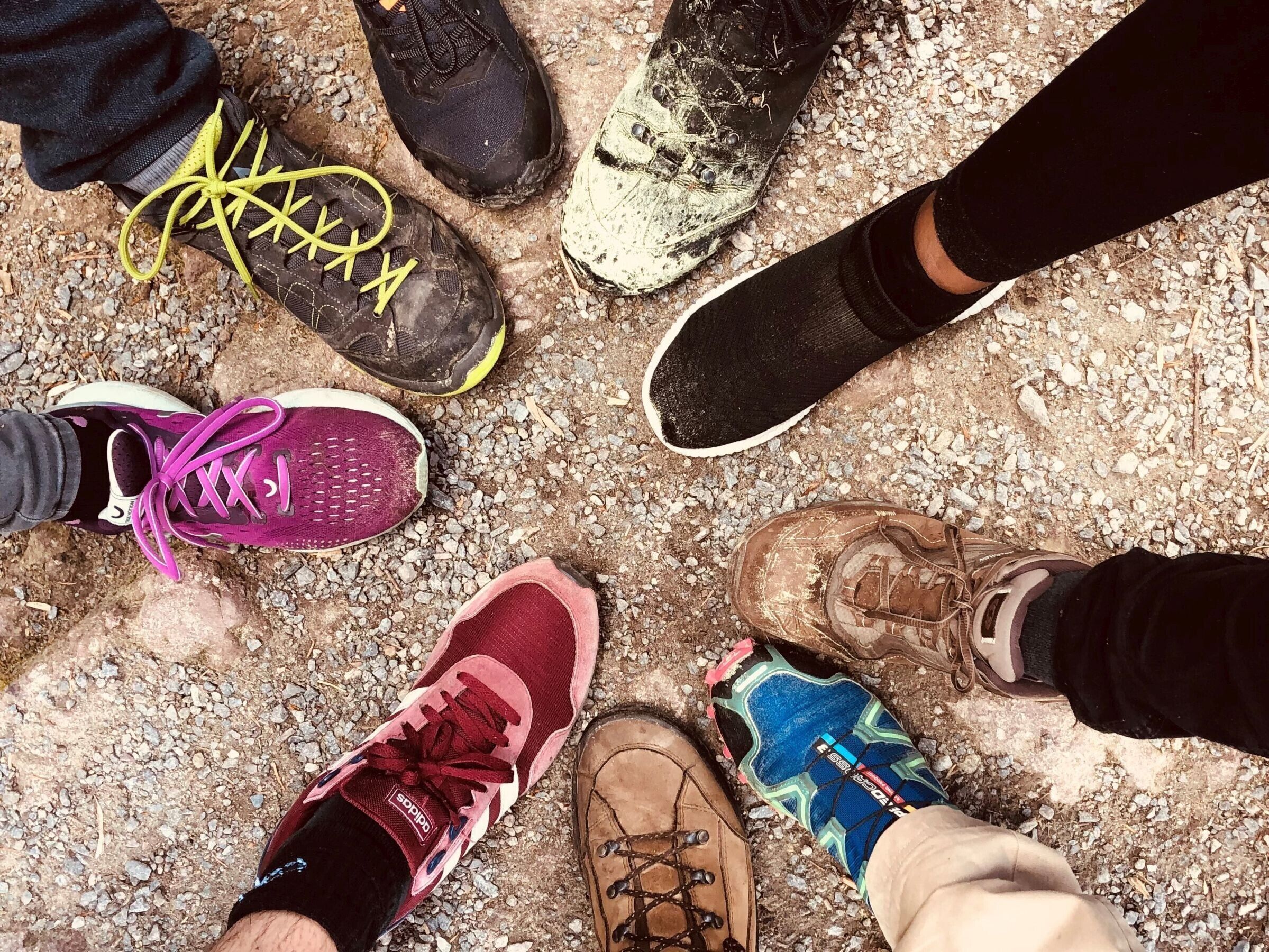 Un groupe de personnes se tient en cercle, chacune portant un type de chaussures différent.