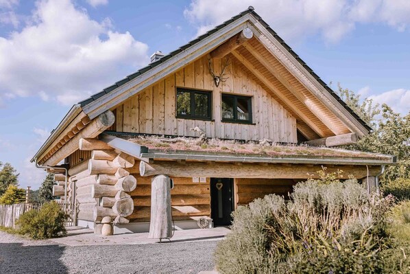 A log cabin with a sloped roof, a front porch, and a small garden area. - Wiesenchalet Holiday Home – Sauerland with Mountain Views, Private Terrace & Wi-Fi (Schalksmühle)