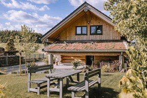 A wooden cabin with a pitched roof, a stone foundation, and a small porch with benches. - Wiesenchalet Holiday Home – Sauerland with Mountain Views, Private Terrace & Wi-Fi (Schalksmühle)