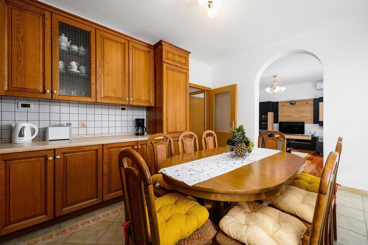 A kitchen with wooden cabinets, a dining table with chairs, and a kitchen island.