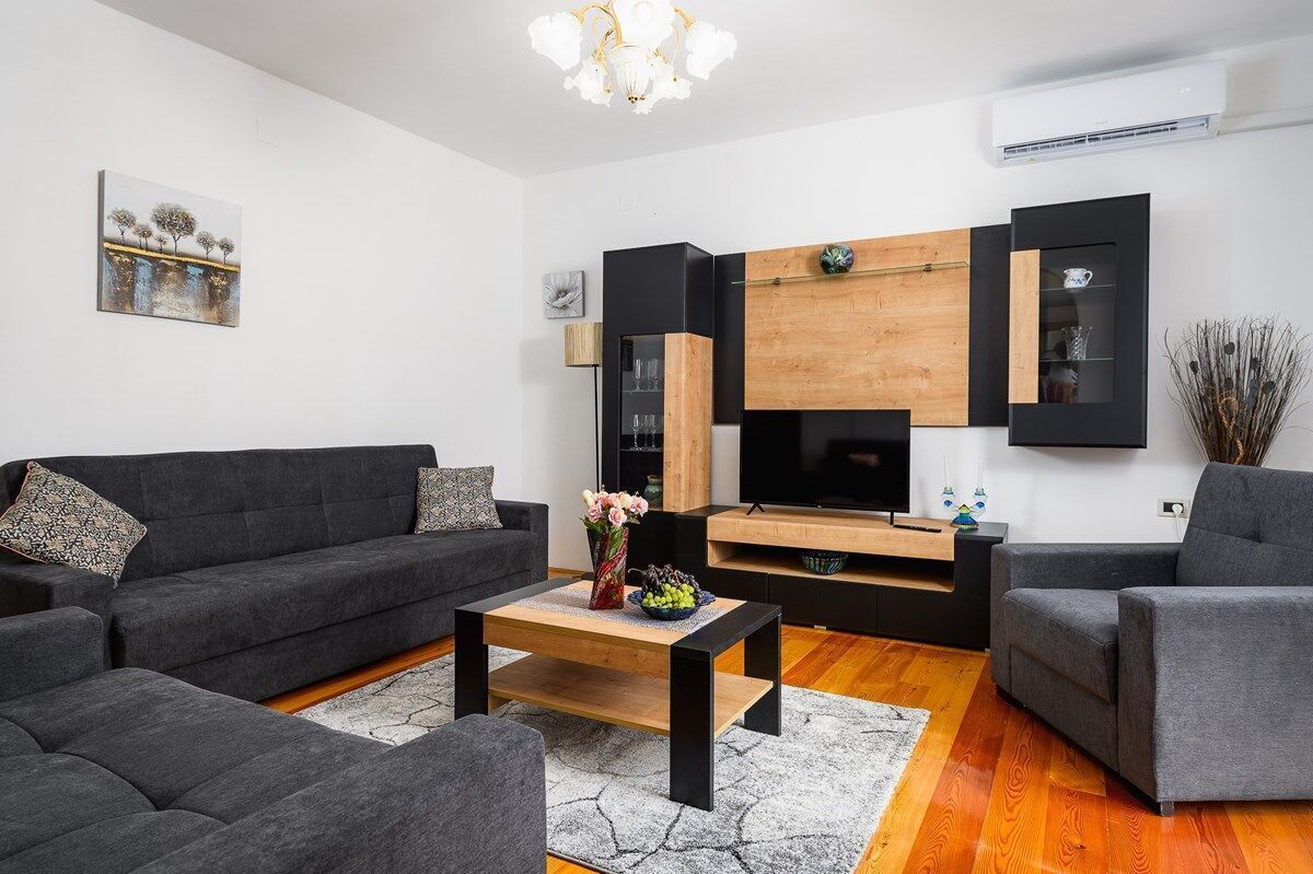 En moderne stue med en grå sofa, et sofabord og et TV-møbel med et fladskærms TV.