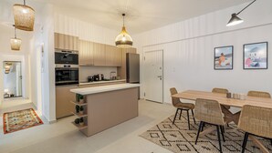 A modern kitchen with a central island, a dining area with wicker chairs, and a ceiling with a unique design. - Cozy and Spacious Apartment close to the Acropolis (Athina)