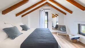 A bedroom with a bed, pillows, a chair, a window, and wooden beams on the ceiling. - House Lando (74318-K1) - Pula (Pula)