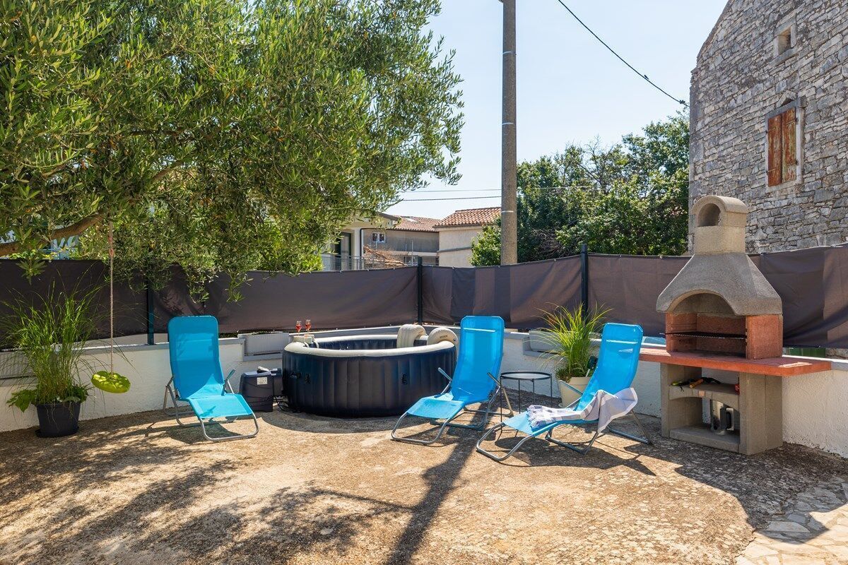 Terrassa exterior amb un edifici de pedra, una banyera d'hidromassatge i seients de relaxació.