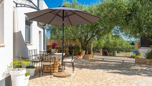 An outdoor patio with stone flooring, a table with chairs, and an umbrella. - House Lando (74318-K1) - Pula (Pula)