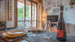 Una mesa de comedor con platos, vasos y una botella de vino etiquetada 'PHILEMA' en una habitación con chimenea y cuadros en la pared.