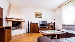 Ett vardagsrum med en öppen spis, träskåp, en tv och en soffa.